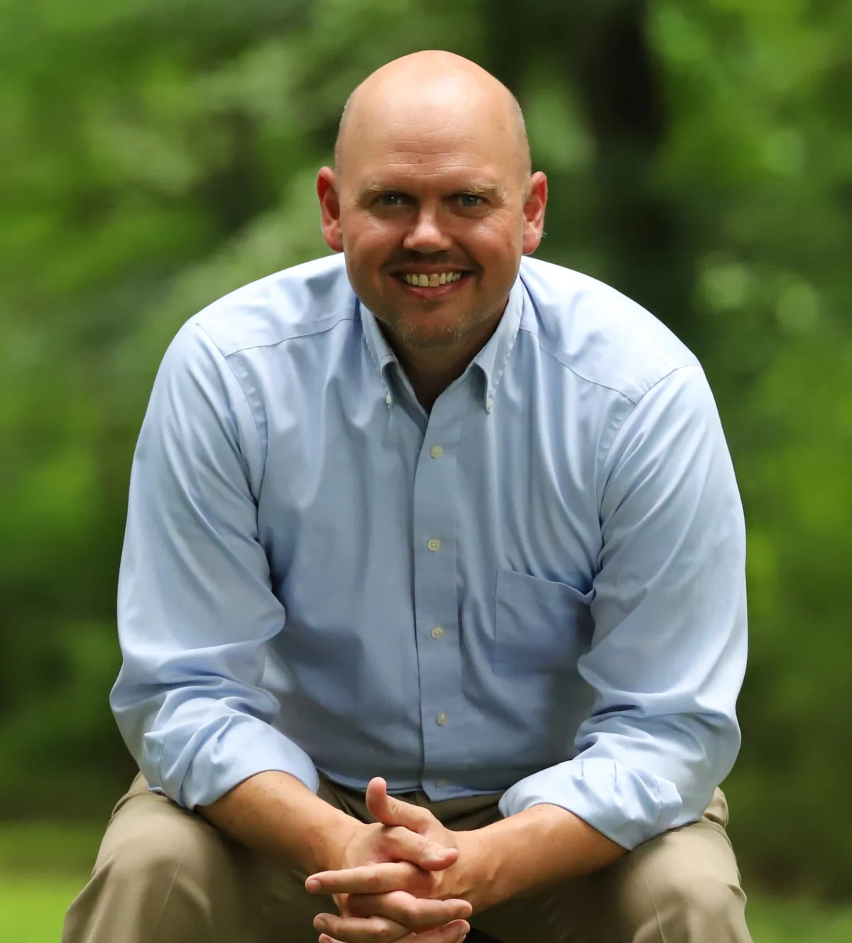 Jeff D. Harmon seated outdoors, leaning forward and smiling
